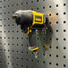 A yellow and black drill on a metal pegboard with a Triton Products double rod.