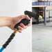 A hand holding a hose with a Regency double trigger spray nozzle.