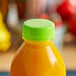 A bottle of orange juice with a lime green tamper-evident cap.