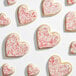 A collection of heart-shaped cookies decorated with white icing and red sanding sugar.