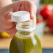 A hand opening a bottle of green juice with a White Unlined Tamper-Evident Cap.