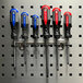 A group of Triton Products stainless steel multi-ring tool holders with screwdrivers on a peg board.