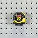 A tape measure on a grey pegboard with Triton Products LocHook BinClips.