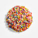 A round treat covered in colorful natural rainbow sprinkles.