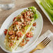 A salad on a plate with romaine lettuce and tomatoes.