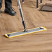 A person using a Lavex yellow microfiber mop to clean a floor.