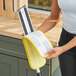 A woman using a yellow and white Lavex microfiber mop pad.