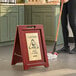 A woman holding a mop and a Lavex Wood A-Frame Wet Floor sign.