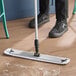 A 24-inch microfiber hook and loop scrubbing wet mop pad being used to clean a wooden floor.
