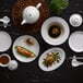 A white porcelain Luzerne condiment dish on a table with food.