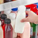 A person holding a 12 oz. Square Milkman clear juice bottle with pink liquid.