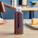 A Square PET clear juice bottle filled with liquid on a table.