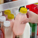 A hand holding a clear Square Milkman juice bottle with yellow liquid.