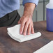 A hand wiping a table with a white Lavex microfiber cloth.