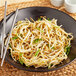 A bowl of fresh bean sprouts with chopsticks on a plate.