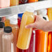 A hand holding a 16 oz. round clear PET juice bottle with white lid.