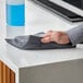 A hand using a black Lavex microfiber cloth to clean a counter.