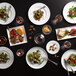 A table with Luzerne Sentosa porcelain square plates of food and glasses.