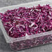 A plastic container of shredded red cabbage on a counter.