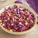 A bowl of shredded red cabbage salad with chickpeas on a table.