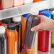 A person holding a 12 oz. round PET clear juice bottle filled with orange liquid.