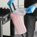 A person wearing blue gloves using a pink Lavex microfiber mop pad to clean a kitchen counter.