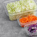 Plastic containers of shredded cabbage and carrots.