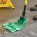 A person using a Lavex green microfiber strip mop with a green cloth to clean a floor.