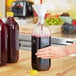 A person pouring juice into a 59 oz. Square PET clear juice bottle.