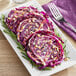 A plate with a whole red cabbage and pine nuts on it.