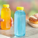 A person holding a Square PET clear juice bottle with yellow liquid.