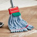 A person mopping a wood floor with a Lavex blue microfiber tube mop with a red headband.