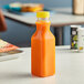 A Square PET clear juice bottle with a yellow lid on a table.