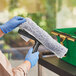 A hand using an Ettore microfiber window washer sleeve to clean a window.