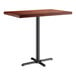 A Lancaster Table & Seating rectangular bar height table with a mahogany wood top and cast iron base.