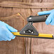 A person in blue gloves holding a black and yellow Ettore squeegee handle.