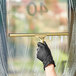 A brass squeegee with a rubber blade being used to clean a window.