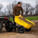 A man using a Gorilla steel dump trailer to transport yellow dirt.