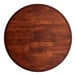 A Lancaster Table & Seating round wood table with mahogany finish on a cast iron base plate.