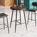 A Lancaster Table & Seating Mid-Century bar height table with butcher block top and espresso finish with two bar stools.