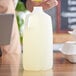 A person pouring a liquid into a translucent plastic jug with a handle.