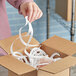 A person cutting white spiral tissue paper in a box.