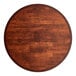 A Lancaster Table & Seating round wooden table top with a mahogany finish on a table.