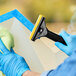 A hand using an Ettore Scrapemaster window scraper to clean a window.