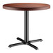 A Lancaster Table & Seating round wooden table with mahogany finish and a black base plate.