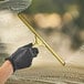 A person wearing a black glove using an Ettore brass squeegee to clean a window.