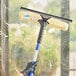 A hand using an Ettore Backflip squeegee to clean a window.