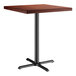 A Lancaster Table & Seating square bar height table with a mahogany wood top and cast iron base.