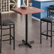 A Lancaster Table & Seating square bar table with a mahogany finish and cast iron base plate.