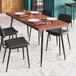 A Lancaster Table & Seating butcher block table with chairs, plates, and forks.